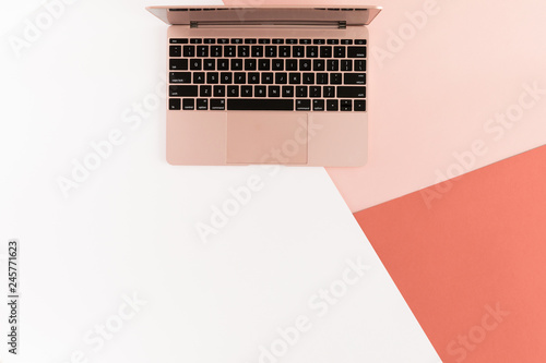 Top view of modern pink gold air laptop on white, pink and coral background. Flat lay photo