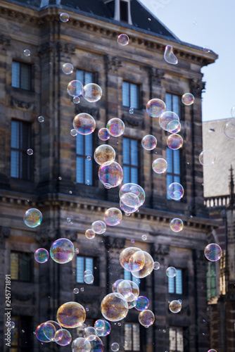 Soap bubbles in the air illuminated by a summer sun in front of a historic building in the big city.