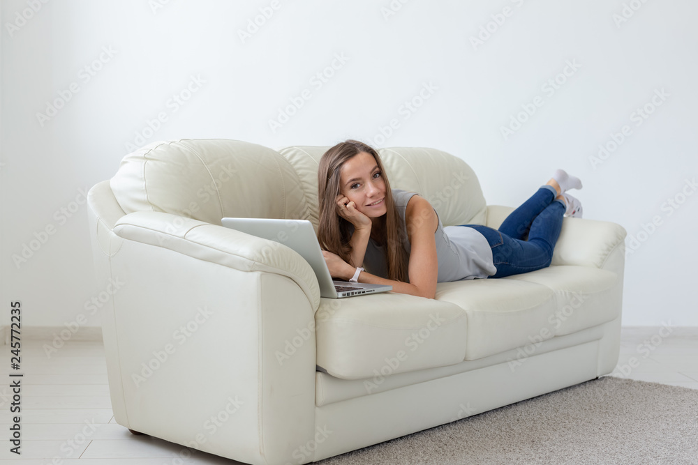 Technologies, relax and people concept - pretty young woman lying on sofa and chatting at home Technologies, relax and people concept - pretty young woman lying on sofa and chatting at home