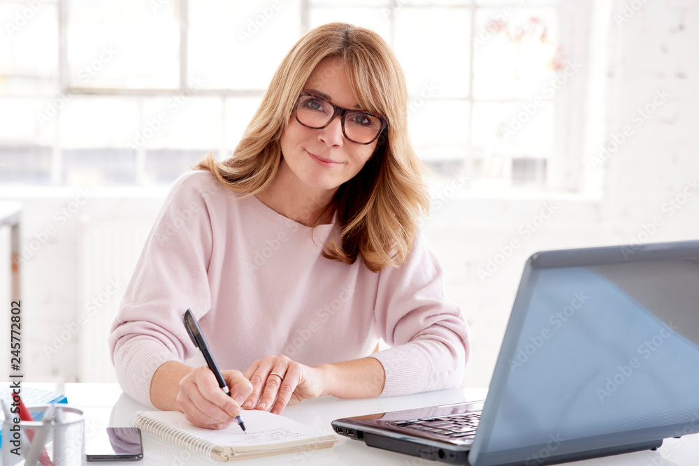 Middle aged businesswoman sitting at office desk and working on business plan Middle aged businesswoman sitting at office desk and working on business plan