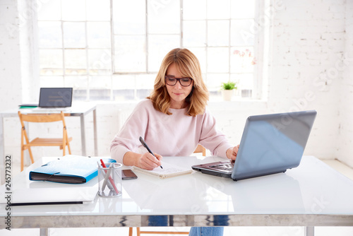 Middle aged businesswoman sitting at office desk and working on business plan