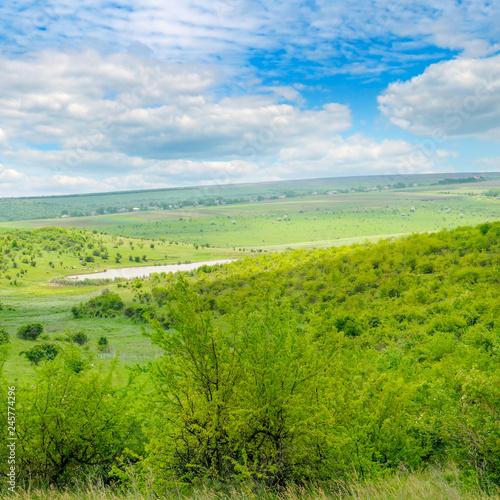 Green field and blue sky. Picturesque hills formed by an old river terrace. Moldova. Agricultural landscape.