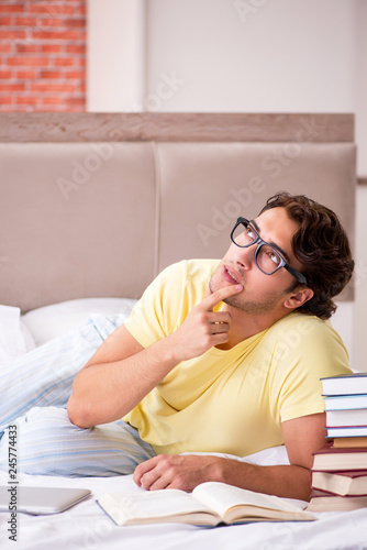 Young student studying in bed for exams