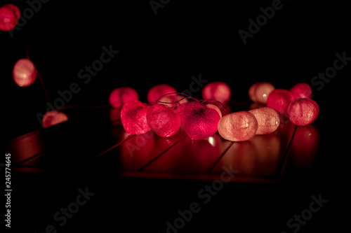 Closeup heart shape of led lights line puts on the wooden table decorated in the darkroom photo