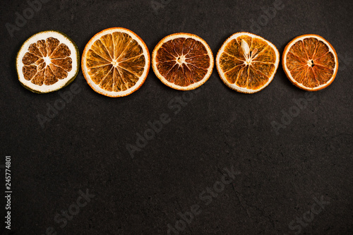 Fototapeta Naklejka Na Ścianę i Meble -  Close up photo of slices of dried orange orranged in a line on a brown background. Organic food concept.