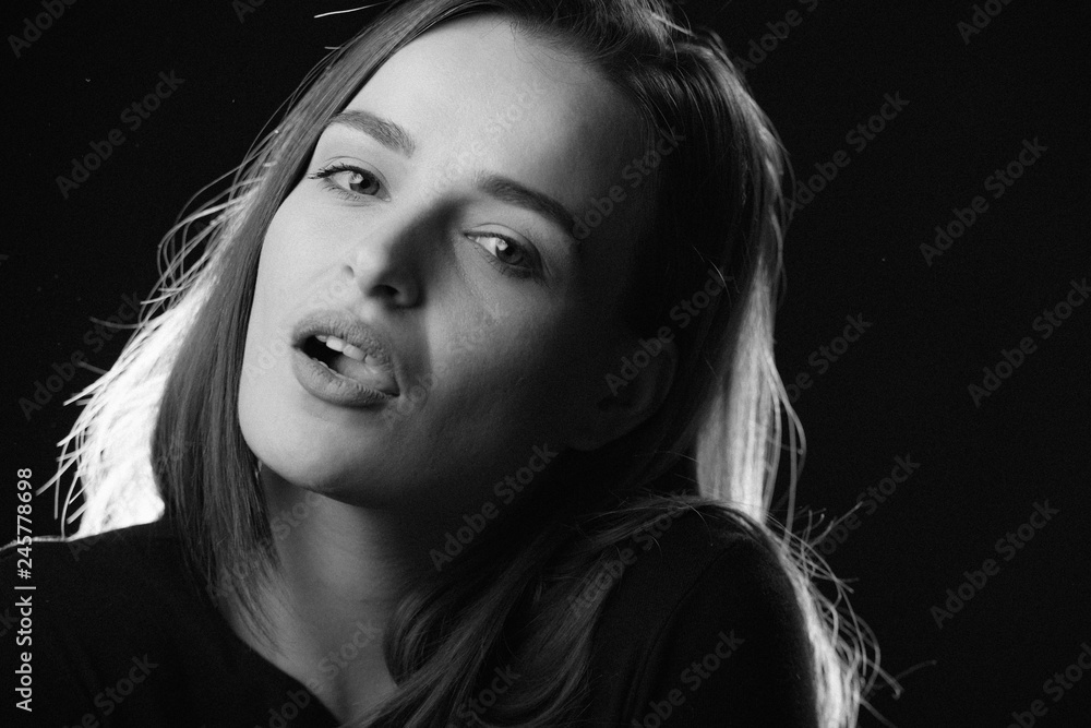 Sexy model with opened mouth looking at camera on black background. Black and white photo portrait of a girl who looks at the camera. Close-up Sexy model with opened mouth looking at camera on black background. Black and white photo portrait of a girl who looks at the camera. Close-up