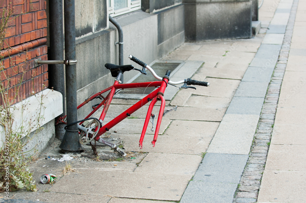 Bicycle remains tethered to a drainpipe on a deserted street
