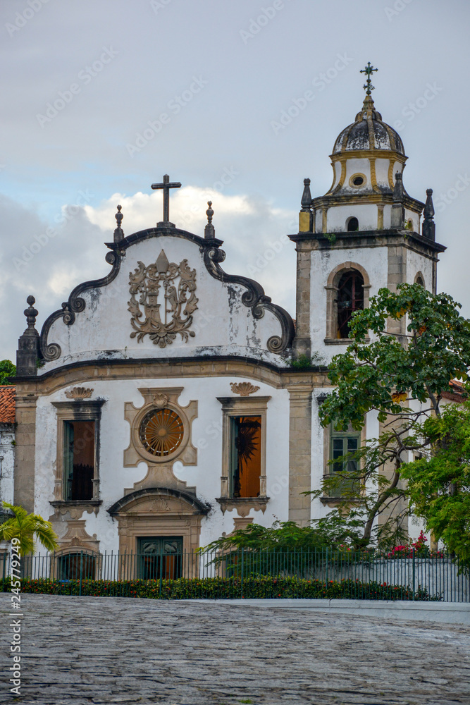 The historic architecture of Olinda in Pernambuco, Brazil showcasing The Mosteiro de Sao Bento church with its Baroque facade and cobble stone pathway on a sunny day.