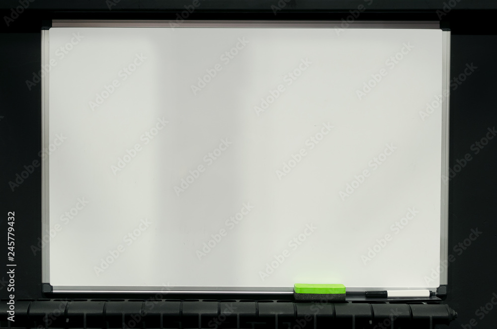 Blank white blackboard with copy space hanging on the black wall background.