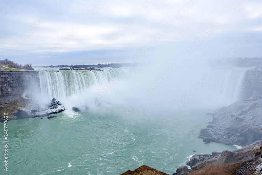 Scenic view of Horseshoe Falls on Niagara river in Canada. Beautiful depressive winter look of largest cascade of famous Niagara falls from Canadian side of border Scenic view of Horseshoe Falls on Niagara river in Canada. Beautiful depressive winter look of largest cascade of famous Niagara falls from Canadian side of border