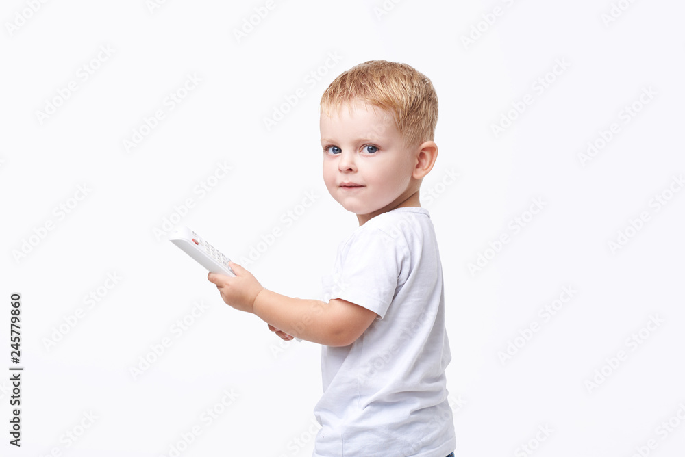 Small blond boy in white clothes holding TV remote control on white isolated background Small blond boy in white clothes holding TV remote control on white isolated background