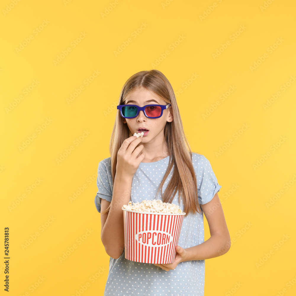 Emotional teenage girl with 3D glasses and popcorn during cinema show on color background Emotional teenage girl with 3D glasses and popcorn during cinema show on color background