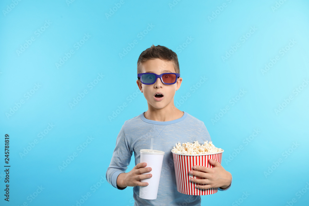 Emotional boy with 3D glasses, popcorn and beverage during cinema show on color background Emotional boy with 3D glasses, popcorn and beverage during cinema show on color background