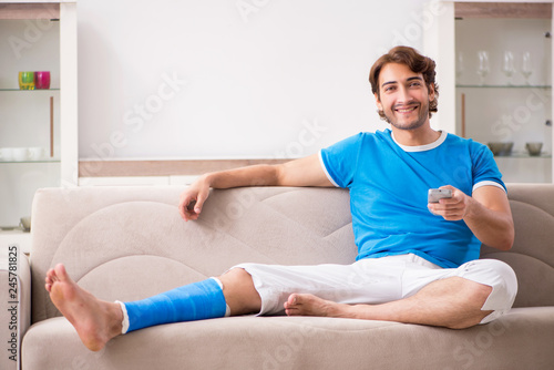 Leg injured young man on the sofa