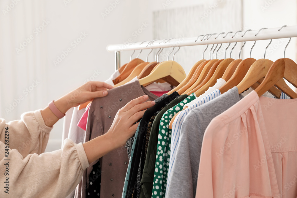 Woman choosing clothes from wardrobe rack, closeup - obrazy, fototapety, plakaty 