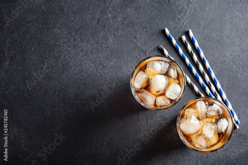 Glasses of refreshing cola with ice cubes on grey background, top view. Space for text
