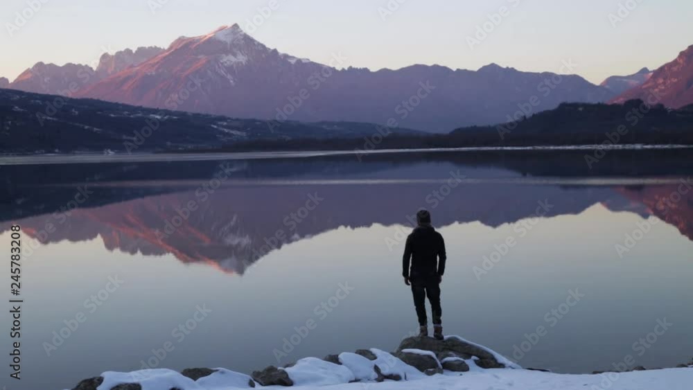 Man reaches rock above lake, arms outstretched. Man reaches rock above lake, arms outstretched.