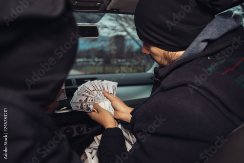 After the successful bank robbery, the thieves are sitting in the car showing off their money and celebrating the win over the law they had.
