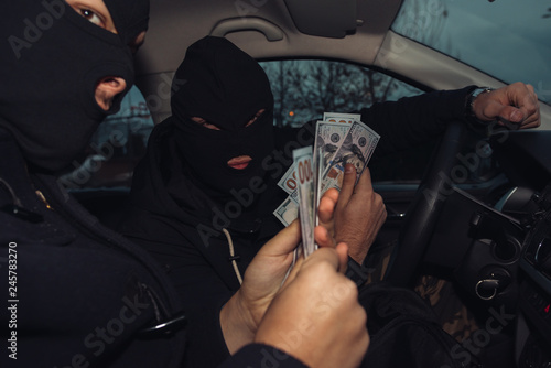 Two masked robbers counting the money they made while sitting in the car they us Fototapet