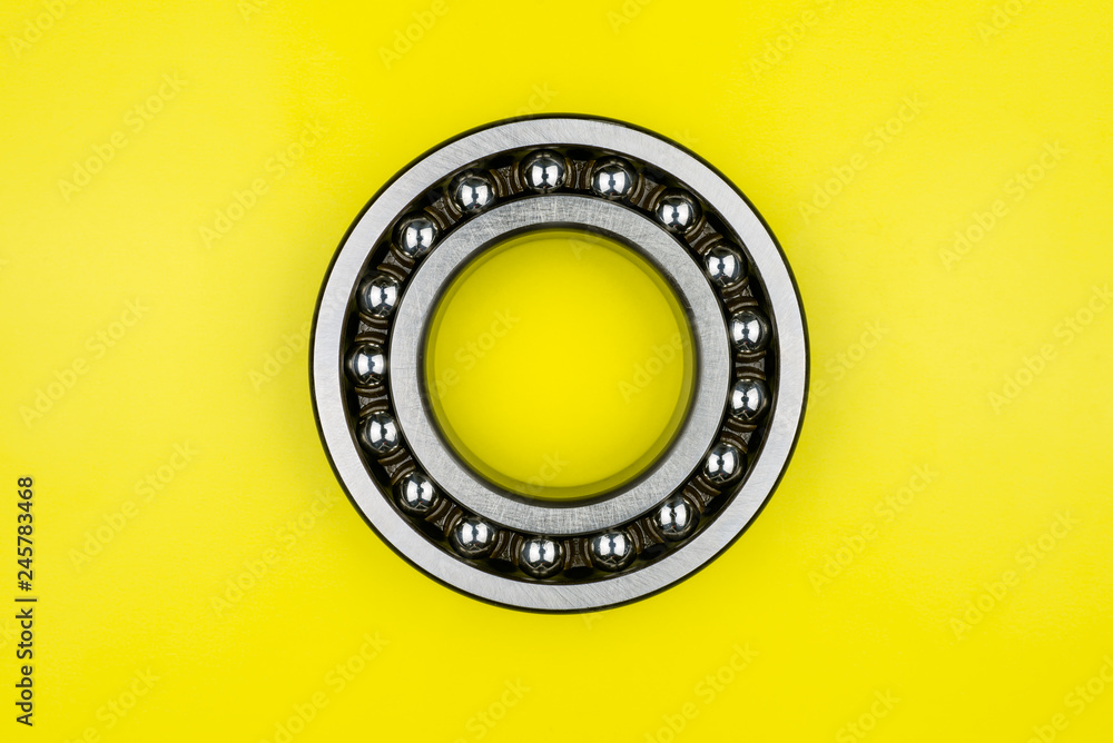 Ball bearing lying on a yellow background with copy space on the sides. Flat view from above. Ball bearing lying on a yellow background with copy space on the sides. Flat view from above.