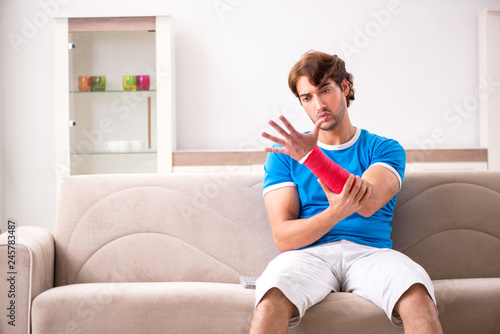 Young man with injured arm sitting on the sofa  © Elnur