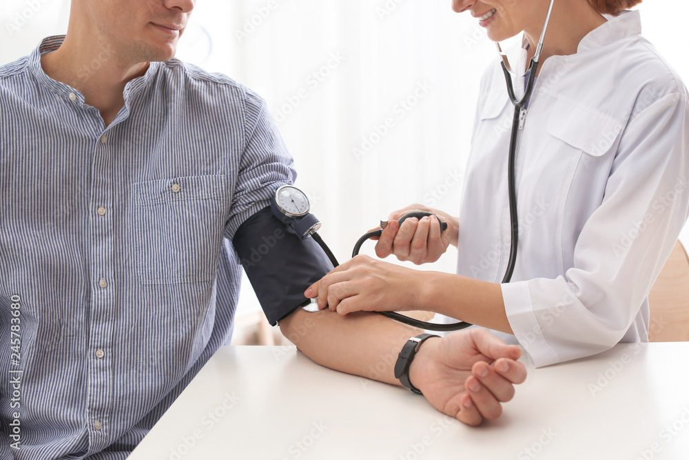 Obraz premium Doctor checking patient's blood pressure in hospital, closeup. Cardiology concept
