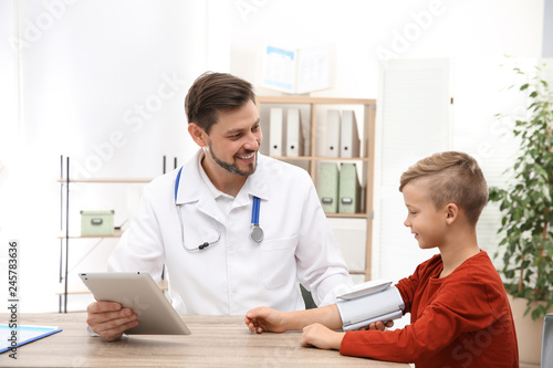 Doctor checking little boy's pulse with medical device in hospital