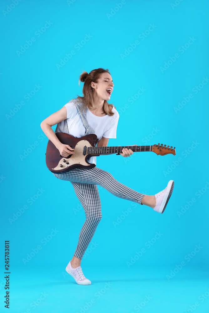 Naklejka premium Young woman playing electric guitar on color background