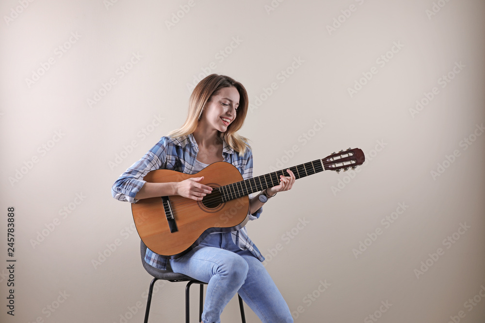 Young woman playing acoustic guitar on grey background Young woman playing acoustic guitar on grey background
