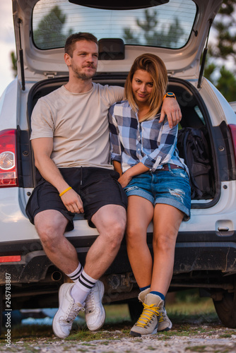 Young couple sitting on the back of a off road vehicle and enjoying the view from inside the all terrain vehicle at sunset. © qunica.com