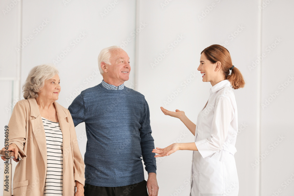 Elderly spouses with female caregiver in room Elderly spouses with female caregiver in room
