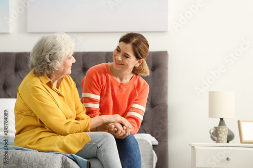 Elderly woman with female caregiver in bedroom. Space for text
