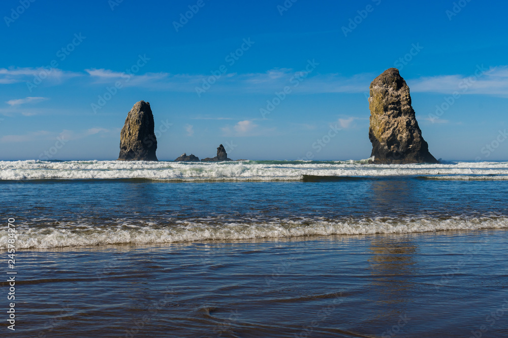 Waves crashing on vertical rocks protruding in Cannon Beach, Oregon, USA. Waves crashing on vertical rocks protruding in Cannon Beach, Oregon, USA.