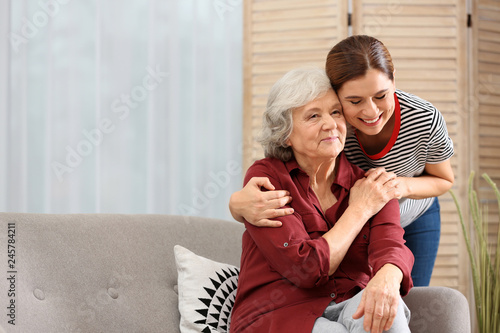 Elderly woman with female caregiver in living room. Space for text photo