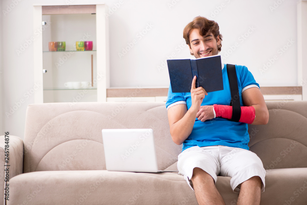 Young man with injured arm sitting on the sofa Young man with injured arm sitting on the sofa