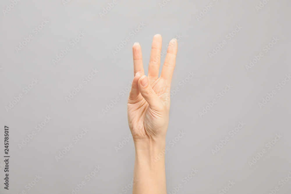 Woman showing number six on grey background, closeup. Sign language Woman showing number six on grey background, closeup. Sign language