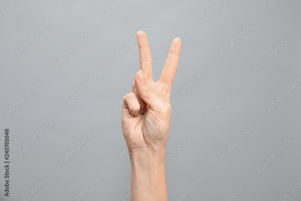 Woman showing number two on grey background, closeup. Sign language Woman showing number two on grey background, closeup. Sign language