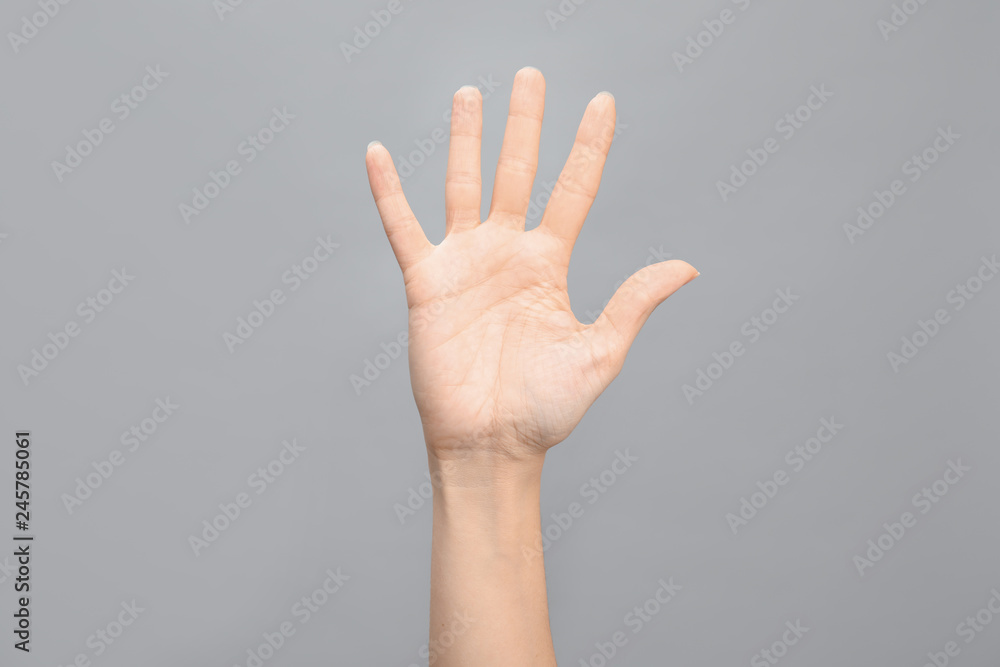 Woman showing number five on grey background, closeup. Sign language Woman showing number five on grey background, closeup. Sign language