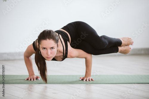 Yoga and Fitness. Young woman sitting in Astavakrasana yoga pose at home