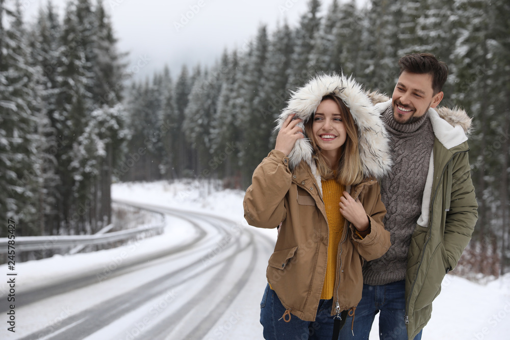 Couple walking near snowy forest, space for text. Winter vacation Couple walking near snowy forest, space for text. Winter vacation