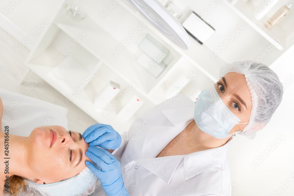 Obraz premium Female beautician doctor with patient in wellness center. Professional cosmetologist make procedure to beautiful girl in cosmetology cabinet or beauty parlor.