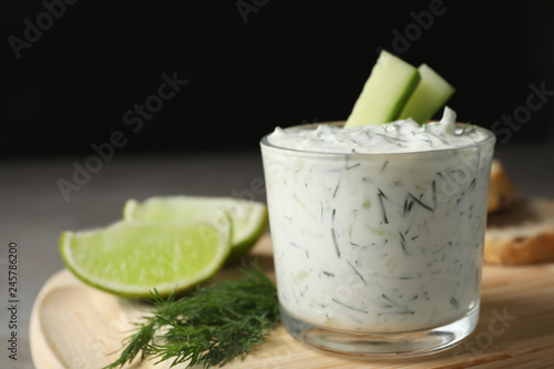 Glass bowl of Tzatziki cucumber sauce on wooden board, space for text
