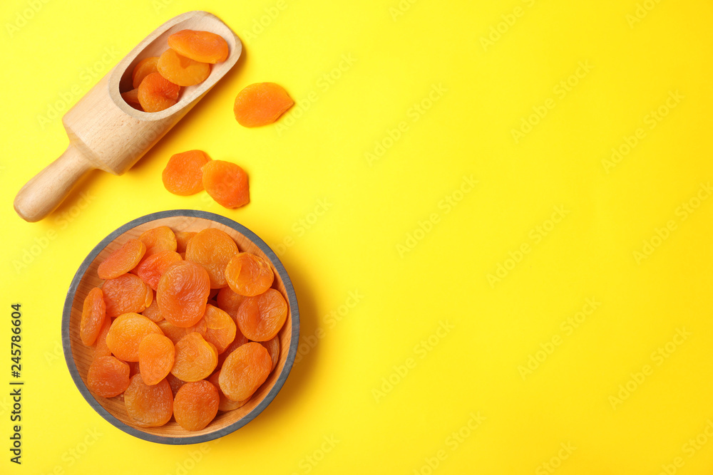 Bowl and scoop of dried apricots on color background, top view with space for text. Healthy fruit Bowl and scoop of dried apricots on color background, top view with space for text. Healthy fruit