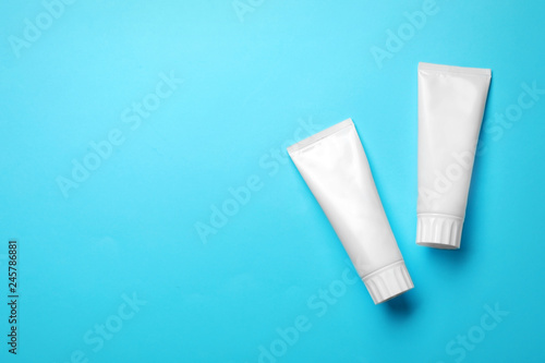 Blank tubes of toothpaste on color background, top view with space for text