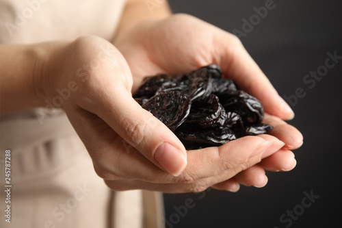 Woman holding handful of dried plums, closeup. Healthy fruit