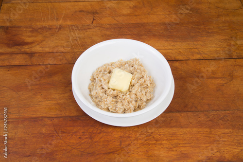 Melting butter on hot oatmeal on rustic wooden background