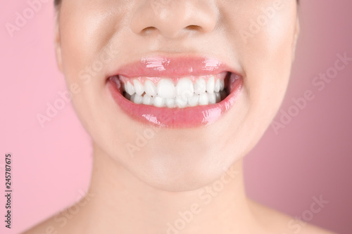 Beautiful young woman with healthy teeth on color background  closeup