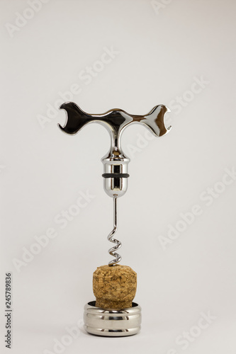 metal corkscrew screwed into the cork on a white background