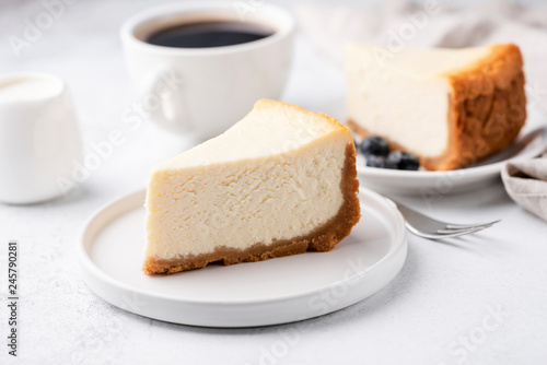 Cheesecake New York with cup of coffee on white table. Closeup view. Coffee break with slice of cake and black coffee