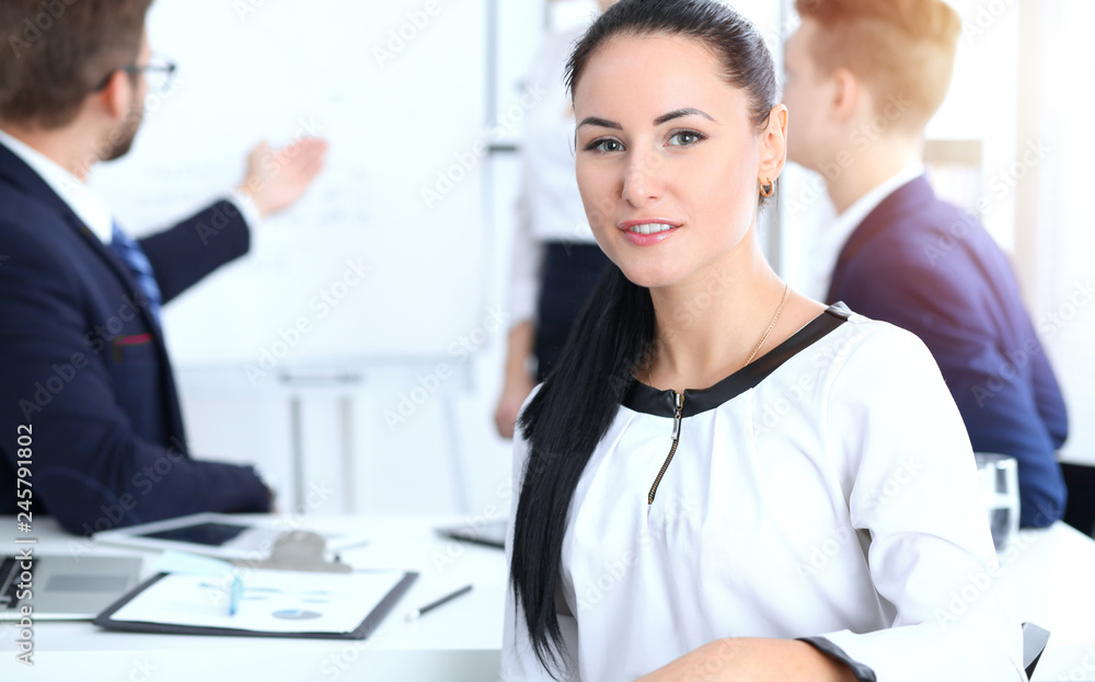Business People group at meeting in office. Focus at beautiful cheerful smiling businesswoman. Conference, corporate training or brainstorming of team. Success and negotiation concept Business People group at meeting in office. Focus at beautiful cheerful smiling businesswoman. Conference, corporate training or brainstorming of team. Success and negotiation concept